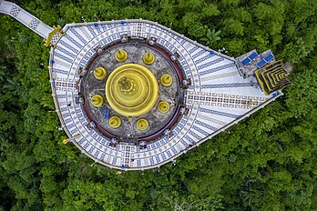 Vista aérea do Templo Dourado de Bandarban, perto da cidade de Balaghata, Bangladesh. É o maior templo budista teravada com a segunda maior estátua de Buda no país. Bandarban tem uma grande população étnica de budistas. O budismo é praticado por uma pequena porcentagem de 0,7 em Bangladesh, um país predominantemente muçulmano. Foi construído em 2000, inspirado na arquitetura arracanesa, uma adoção do estilo do Sudeste Asiático. A relíquia de Buda, que está guardada no templo, foi um presente dado em 1994 pelo Comitê Estadual Sangha Maha Nayaka de Myanmar. (definição 5 039 × 3 357)