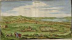 Two men and a lion in the foreground of a landscape showing a green valley across which can be seen a densely-built city -->