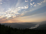 Sunset over a large river flowing through mountains.