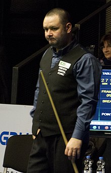 Stephen Maguire stood holding a cue