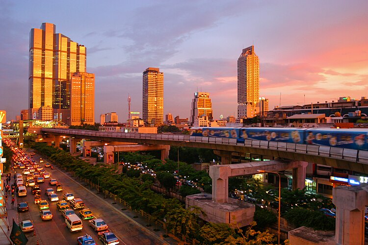 Заход Солнца в Бангкоке. Вид на надземное метро Skytrain и современные небоскрёбы, сфотографировано с угла Thanon Silom