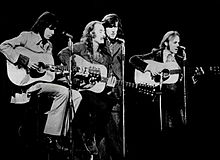 The band seated and performing onstage