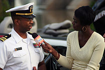 A woman holds a Today's T H V-labeled microphone out to a man in a United States Navy uniform