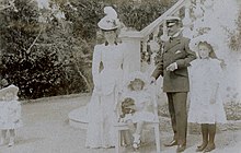 cinq personnes posent sur ce cliché, Geneviève, deux ans, debout et portant un petit chapeau, Henriette debout en tenue claire et coiffée d'un imposant chapeau à plumes, Emmanuel debout en tenue de ville, coiffé d'un képi, tenant un cigare de la main gauche, sa main droite étant posée sur le dossier d'un petit fauteuil sur lequel est assise Sophie coiffée d'une charlotte claire et tenant un petit chien au pelage sombre et debout à droite, Marie-Louise en tenue claire coiffée d'une large capeline