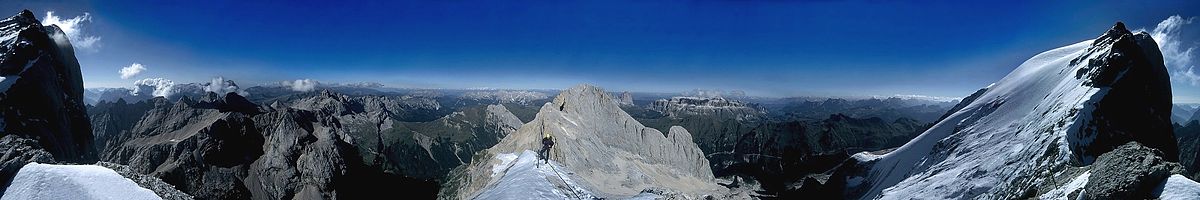 Körkilátás (360°) a Marmolada gerincén, a Punta Penia tövéből. Jobb (és bal) szélen a Punta Penia csúcs (K), balról jobbra a Pale di San Martino (D), a Latemar (DNY), a Rosengarten (Catinaccio, NY), középen maga a főgerinc „élből” (NY), a Langkofel (Sassolungo, ÉNY), a Sella-csoport (É), az Ampezzói-Dolomitok (ÉK-K)