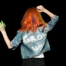 An image of Hayley Williams from behind wearing a denim jacket that reads "GROW UP" in white.