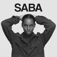 The cover artwork for "Sand". The cover features Saba in a black and white filter. Above her, the words "Sand" are printed in black.