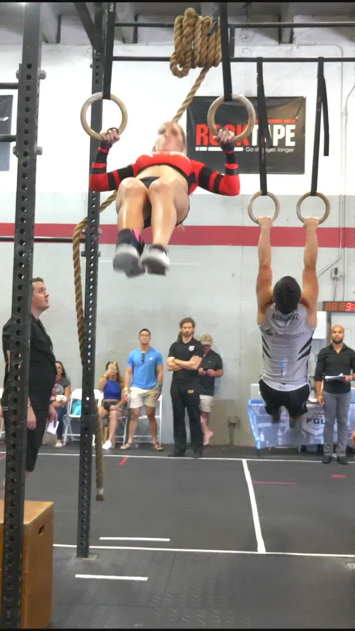 This may contain: a woman doing aerial exercises on rings in a gym