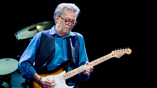 Eric Clapton recebe aplausos e vaias ao tocar música em homenagem a técnico do Liverpool na Inglaterra