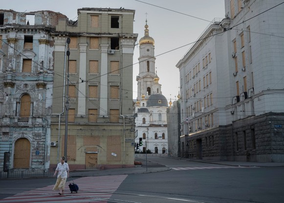 Mulher caminha entre edifícios bombardeados durante a guerra em Kharkiv, no leste da Ucrânia