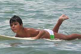 Boy learning to surf in Atlantic Ocean off Barra, Brazil