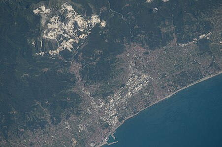 white Marble Mountains of Carrara, part of Alpi Apuane, a remote view with nearby town Massa