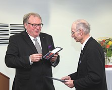 Secretary of State Walter Schumacher handing over the Order of Merit of the Federal Republic of Germany