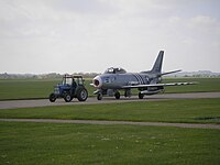 An F-86 Sabre being towed by a tractor at Imperial War Museum Duxford