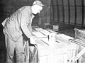 Applying in the cargo assembly area at the contruction battalion center, Davisville, R.I., colored paint to shipping containers as code to indicate its ultimate destination in the Antarctic. A different color code was assigned for each base.