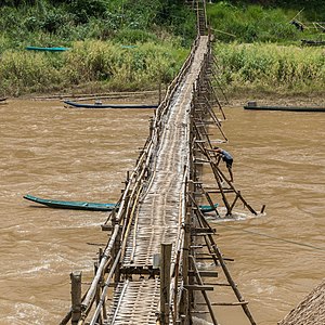 "Wooden_footbridge_in_Luang_Prabang_with_a_worker_busy_at_its_consolidation.jpg" by User:Basile Morin