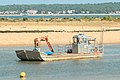 Un bateau ostréicole dans le chenal du Piquey au Cap-Ferret vu depuis la plage du phare avec, en arrière-plan, l’extrémité de la plage du Mimbeau.