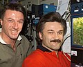 Expedition 8 Commander Michael Foale and Flight Engineer Alexander Kaleri pose beside the pea plants growing in the Lada-4 greenhouse experiment