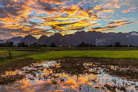 "Colorful_sky_with_orange_clouds_reflecting_in_the_water_of_a_paddy_field,_at_sunset,_Vang_Vieng,_Laos.jpg" by User:Basile Morin