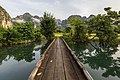 "Front_view_of_a_wooden_footbridge_over_a_lagoon,_trees_and_mountains_in_Vang_Vieng,_Laos.jpg" by User:Basile Morin