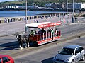 A horse-drawn tram in Douglas, Isle of Man. The man standing on the stepboard is the conductor, who collects the fares.