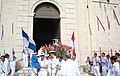 La barque de St-Pierre sort de l'église St-Louis, précédée de la gerbe qui sera jetée en mer. Les jouteurs font une haie d'honneur.