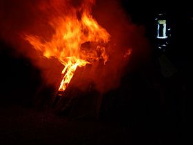 Feuerwehr überwacht brennenden Holzstoß