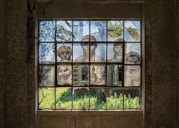 Window in the abandoned Ellis Island Hospital, with photo blown up by artist JR