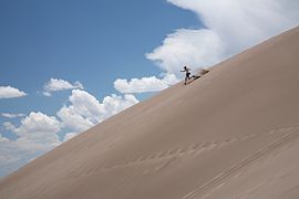 Visitor running down a dune in Great Sand Dunes National Park, USA