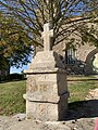 Croix latine et son support en granit à gauche de l'escalier sud à l'extérieur de l'église Saint-Nicodème de Bourseul dans les Côtes d'Armor.