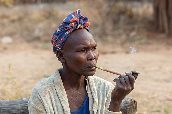 Adult woman of the Laarim Tribe smoking in a pipe, Kimotong, South Sudan.